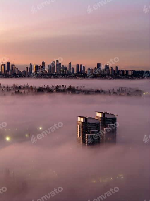 Preview: Sunrise Over Foggy City Skyline With Towering Buildings Emerging From Morning Mist