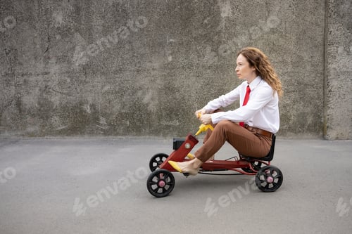 Preview: Funny businesswoman driving retro pedal car outdoor