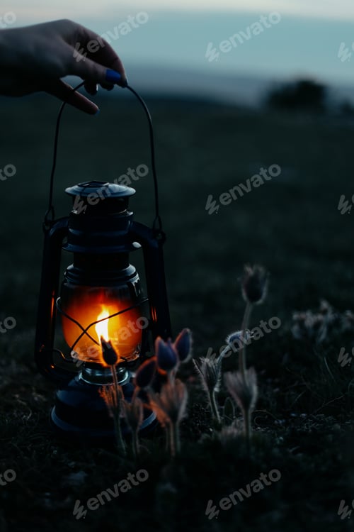 Preview: female hands holding a burning kerosene lamp
