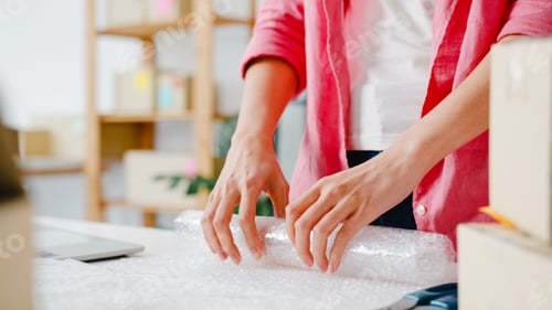 Preview: Young Asia entrepreneur businesswoman packing product in cardboard box deliver to customer
