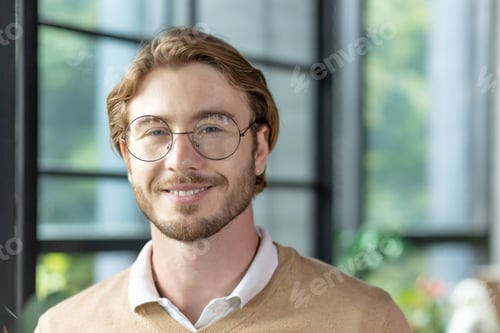 Preview: Close-up portrait of a young man inside the office, a businessman in glasses is smiling and looking