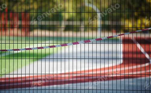 Preview: Red and white prohibitory tape on the fence of the sports complex. Closed for visiting, quarantine