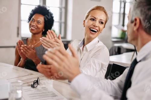 Preview: Happy colleagues applauding during a business meeting in the office.
