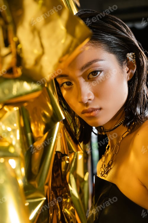 Preview: portrait of glamorous asian young woman with wet short hair posing in strapless dress next to shiny