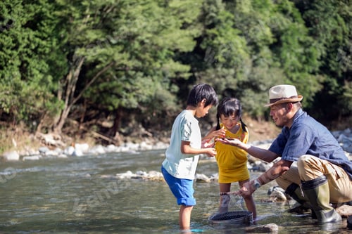 Preview: Father and two children playing by a river.