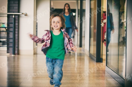 Preview: Little boy running in the shopping center with his mom on background.