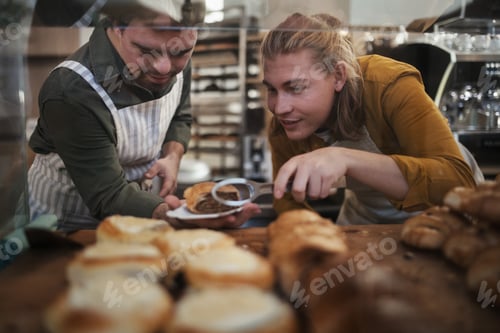 Preview: Man with down syndrom helping his colleague in a cafe, holding fresh pastries. Concept of