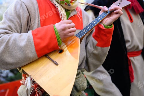 Preview: a man in a winter national Russian costume plays the balalaika