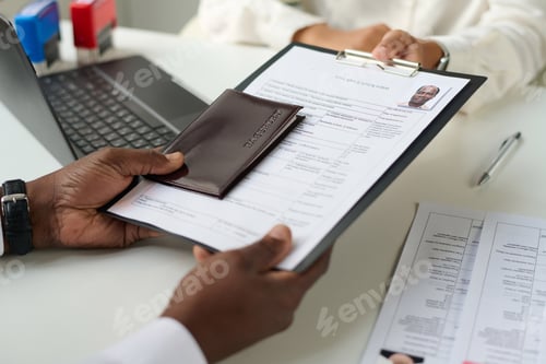 Preview: Close-up of man giving documents to specialist to get visa