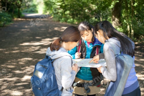 Preview: Three young female hikers looking at map