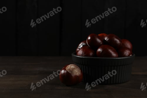 Preview: Brown chestnut fruits in a black bowl on a dark background
