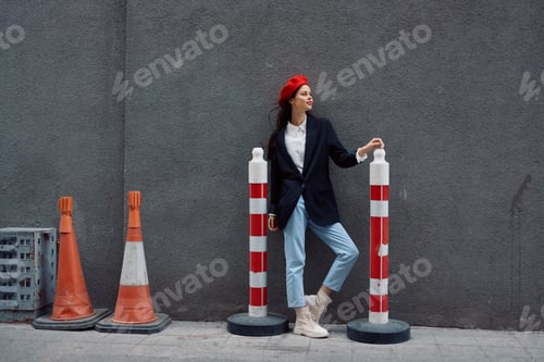 Preview: Fashion woman standing leaning against a wall street against a background of the city road works
