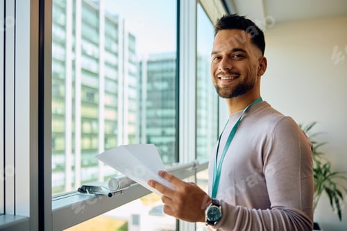 Preview: Happy entrepreneur analyzing business reports in the office and looking at camera.