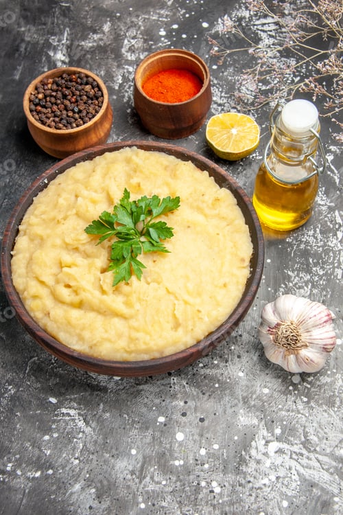 Preview: top view mashed potatoes in wooden bowl pepper red pepper in small bowls oil garlic lemon slice on