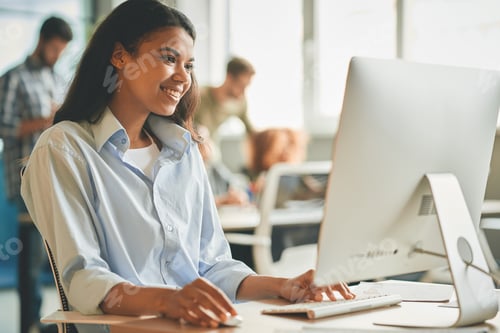 Preview: Joyful female office worker using her workplace computer