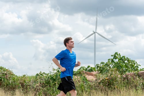 Preview: Caucasian active sportsman running exercise at the wind turbine field.