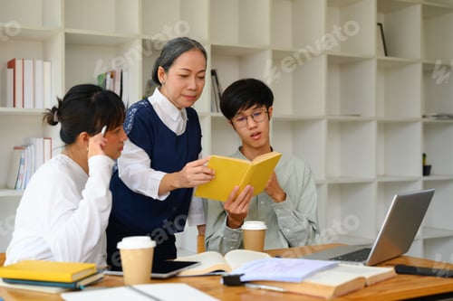 Preview: Mature lecturer helping students with project in classroom. Education concept