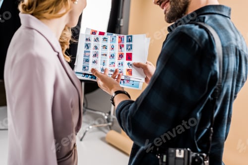 Preview: cropped shot of photographer and model looking at photos in studio