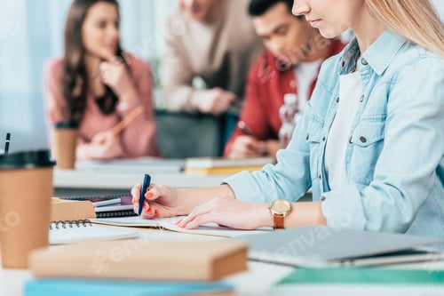 Preview: Cropped view of student writing in notebook in classroom