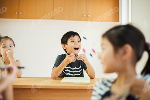 Preview: Three children, a boy and two girls in a classroom.