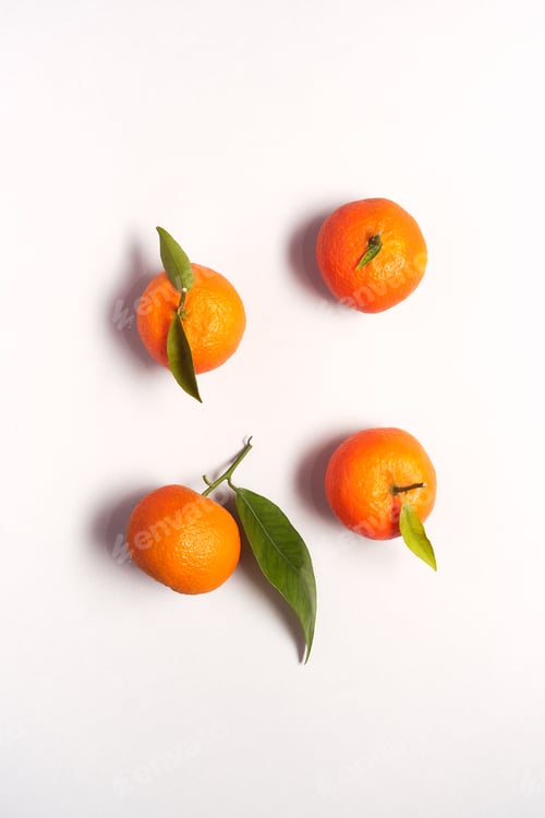 Preview: Overhead View Of Fresh Satsumas With Leaves Against White Background
