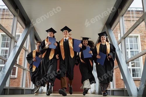 Preview: Multiethnic Young Graduates Running Joyfully Across University Walkway