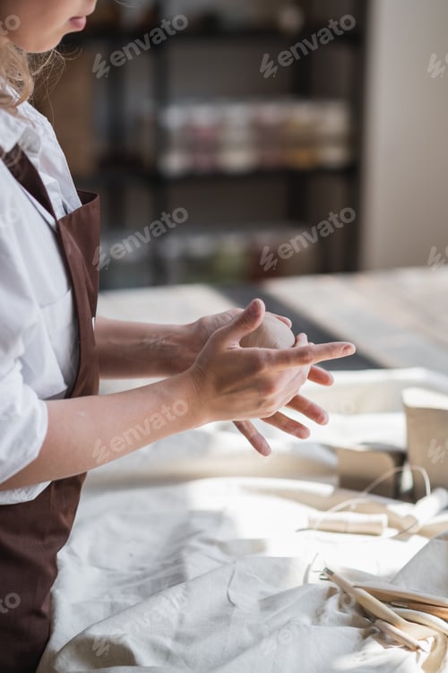 Preview: Female potter shaping piece of clay at the table. Woman making ceramic item. Pottery working