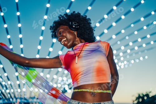 Preview: Young woman dancing with scarf and headphones at music festival