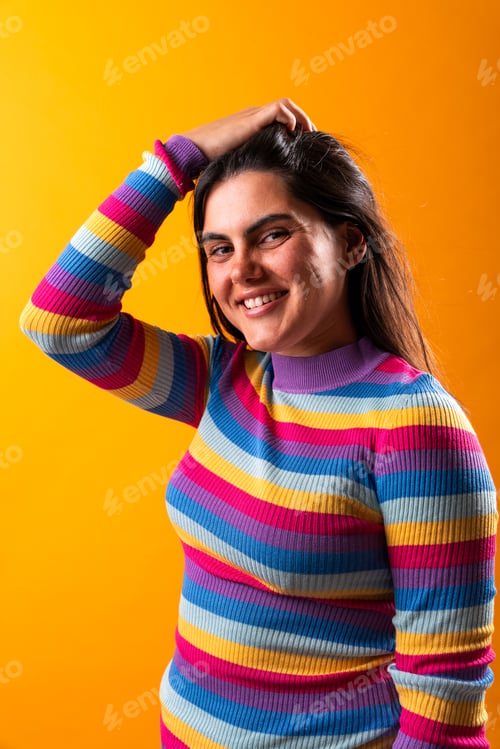 Preview: Young woman smiling and touching hair on orange background