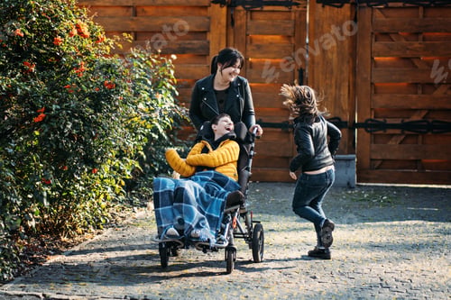 Preview: Mother and sibling bonding with child in wheelchair during outdoor time, special needs care, family