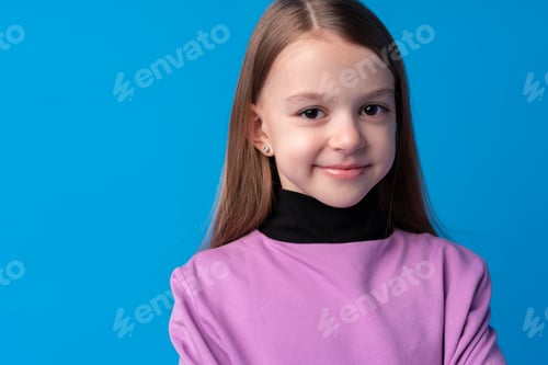 Preview: Portrait of a little smiling girl preteen on blue background