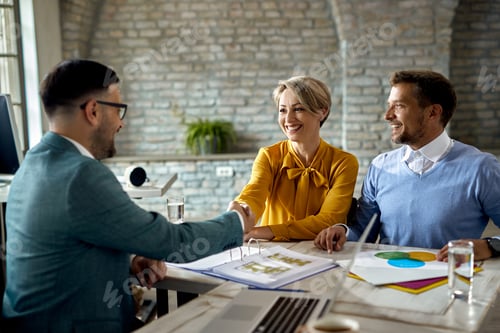 Preview: Happy couple shaking hands with insurance agent in the office.