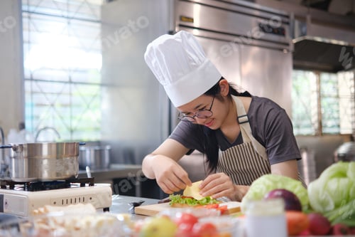Preview: Focused chef carefully a gourmet sandwich in a professional kitchen with fresh ingredients in view
