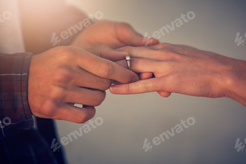 Preview: Cropped shot of a young man putting an engagement ring on his girlfriends finger