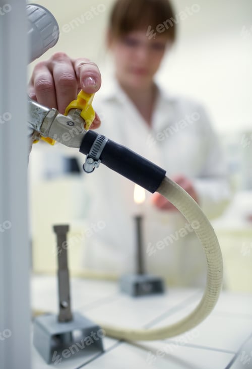 Preview: young and pretty female researcher lighting up a burner in a lab