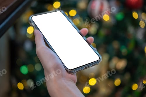 Preview: female hand holding and using a mobile phone mock up with bokeh background.