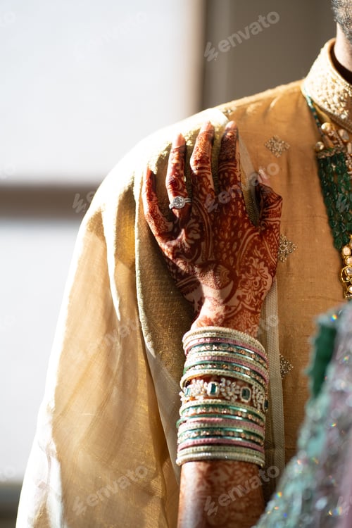 Preview: a groom's hands in different kinds of bracelets and hennakes