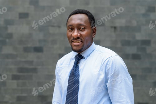 Preview: Portrait of handsome African businessman in city smiling