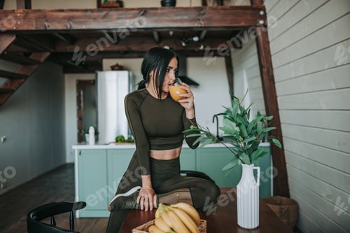 Preview: Woman in Athleisure Drinking Juice in Airy Kitchen