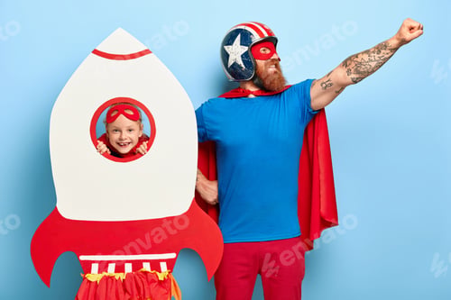 Preview: Glad bearded man looks confidently aside, makes flight gesture, dressed in superhero clothes, cheerf