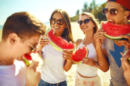Preview: Group of friends having fun eating watermelon on beach. Excellent sunny weather. Super mood. Summer