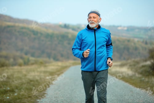 Preview: Motivated senior athlete road running in nature.