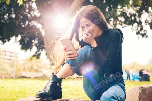 Preview: Young woman using smartphone in park