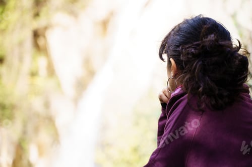 Preview: Close up view of a woman looking at a small waterfall in the forest