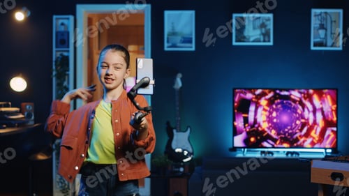 Preview: Joyous kid taking part in viral dance trend filming video with smartphone attached to selfie stick