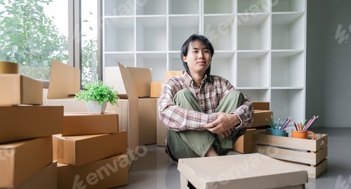 Preview: Handsome asian man in casual clothes siting leaning on pile of large cardboard boxes for moving