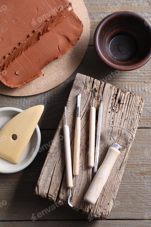 Preview: Clay and set of modeling tools on wooden table, flat lay