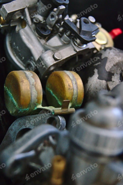 Preview: An old carb is in a box with many other carburetors and carburetor parts.