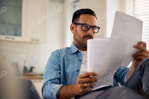 Preview: Focused entrepreneur analyzing business reports at home.