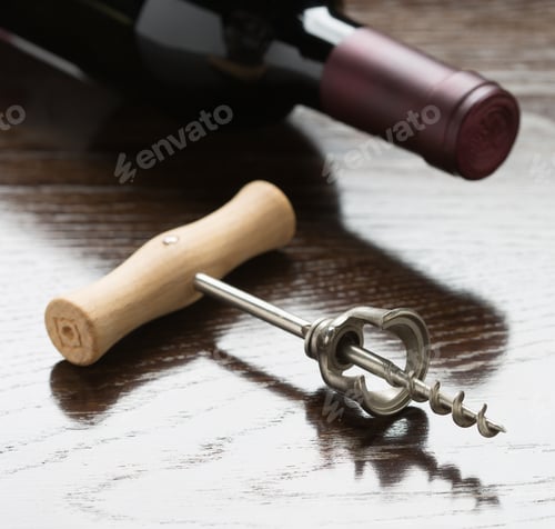 Preview: Abstract Wine Bottle and Corkscrew Laying on a Reflective Wood Surface.